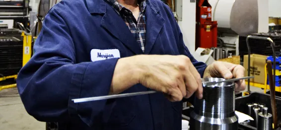 MIR machinist checking a threaded machined part with a rule